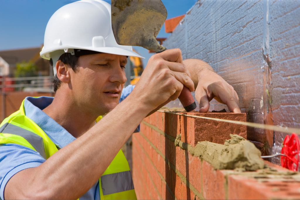 Construction Worker Laying Bricks on New Wall