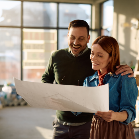 Happy Couple Reviewing Architectural Blueprints in Their New Home Under Renovation